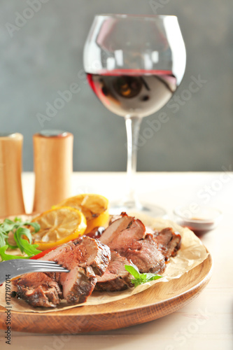 Fork and sliced tasty steak on wooden plate