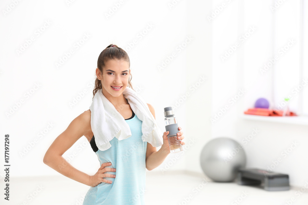 Sporty young woman with bottle of water in gym Sporty young woman with bottle of water in gym