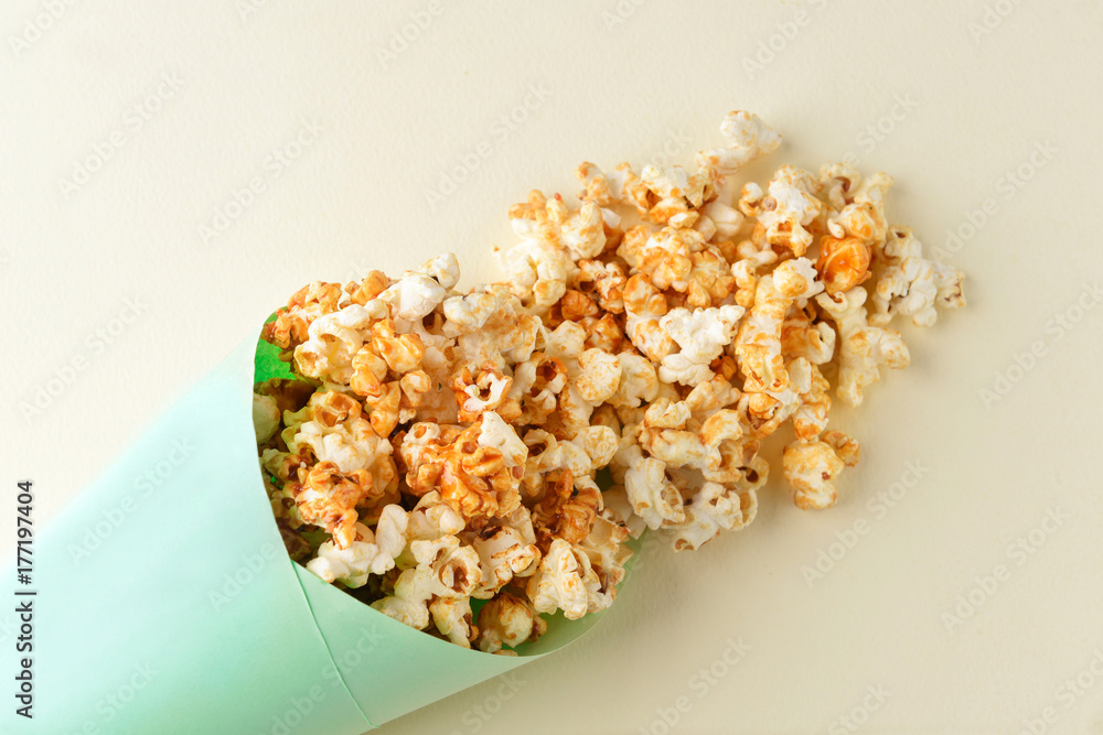 Paper cone with tasty caramel popcorn on light background Paper cone with tasty caramel popcorn on light background