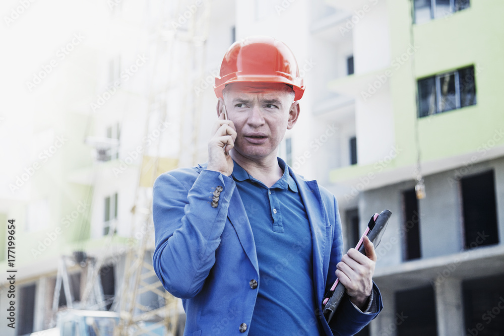 Young аrchitect  man in suit and helmet talking mobile phone on construction site (engineer, construction worker concept)