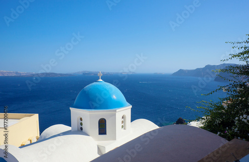 Blue dome of church and blue sea water in Santorini.