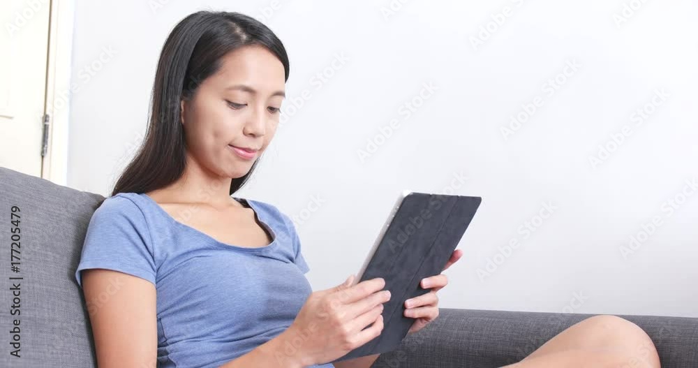 Woman working on tablet computer on sofa Woman working on tablet computer on sofa