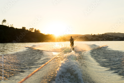 A water skier takes a run at sunset on a empty glassy lake photo