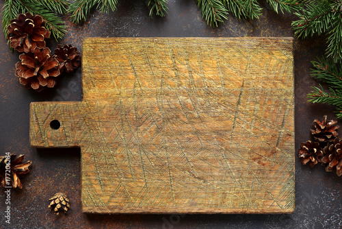 Christmas background with fir branches and empty wooden cutting board with space for text.Top view.