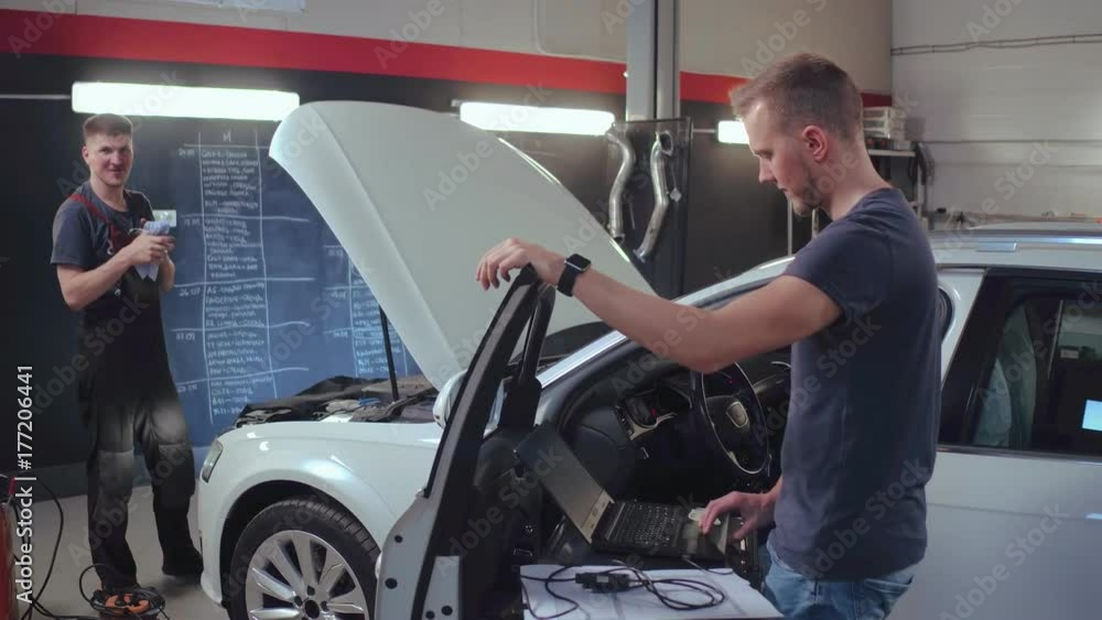 Mechanic man working in repair garage. Car diagnostic in auto service Mechanic man working in repair garage. Car diagnostic in auto service