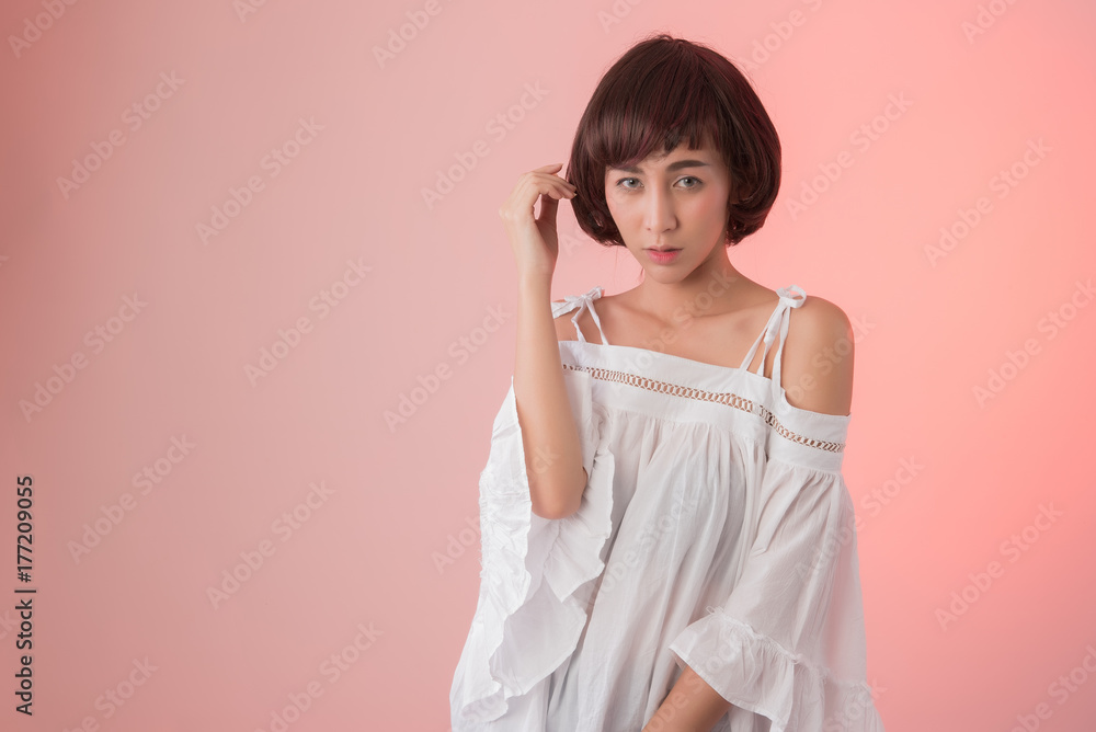 Portrait of beautiful smiling young asian  girl woman with short dark black hair bob, Studio portrait of pretty young Asian woman wearing white dress  on pink background.