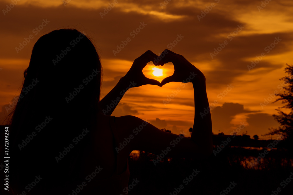 Hands forming a heart shape with sunset silhouette. Hand shaped heart in  the sky. Stock Photo