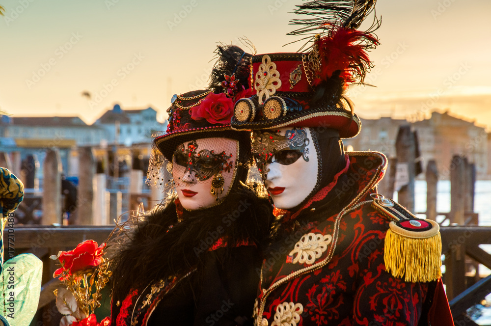 Beautiful couple of masks at Venice Carnival in sunrise near the Canal Grande