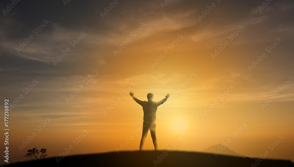 successful concept, Silhouette man stand on the top of mountain and look through the sunrise, sunset and give two hand up to feel like a winner, success, finish,reach a goal of live, jobs,work