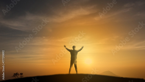 successful concept, Silhouette man stand on the top of mountain and look through the sunrise, sunset and give two hand up to feel like a winner, success, finish,reach a goal of live, jobs,work