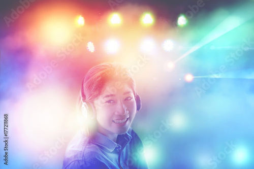 asian pretty woman listening to music in headphones with colorful light background fun like in party