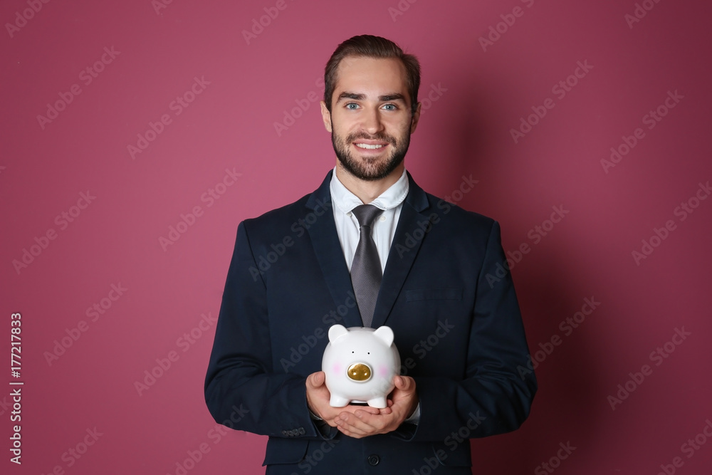 Young man with piggy bank on color background Young man with piggy bank on color background