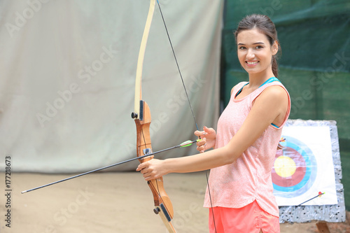 Young woman practicing archery outdoors photo