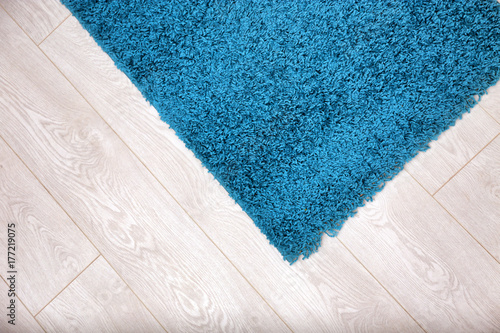 Fotografie Beautiful blue carpet on wooden floor, closeup