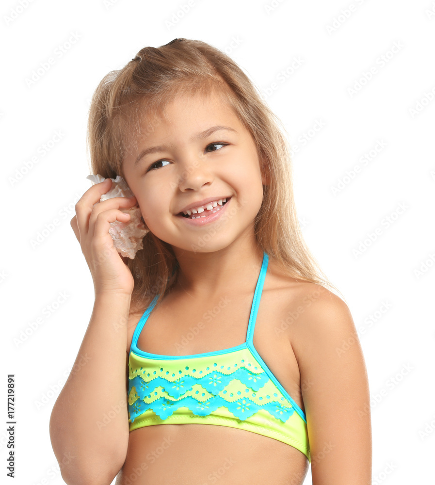 Adorable little girl in swimsuit listening to sea shell on white