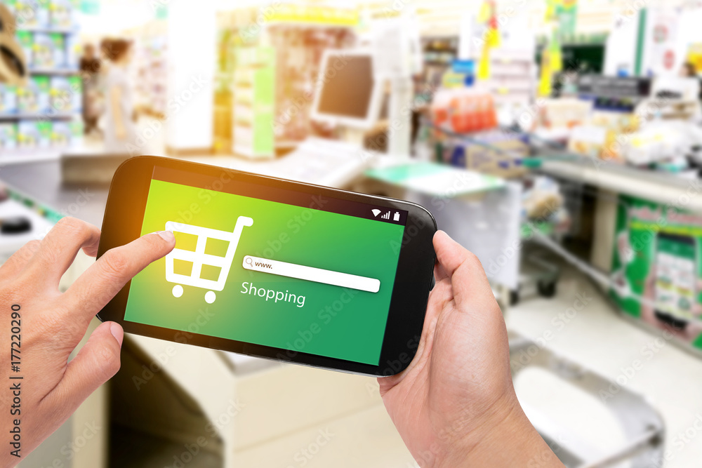 Hand holding mobile phone at supermarket checkout background, e coupon concept