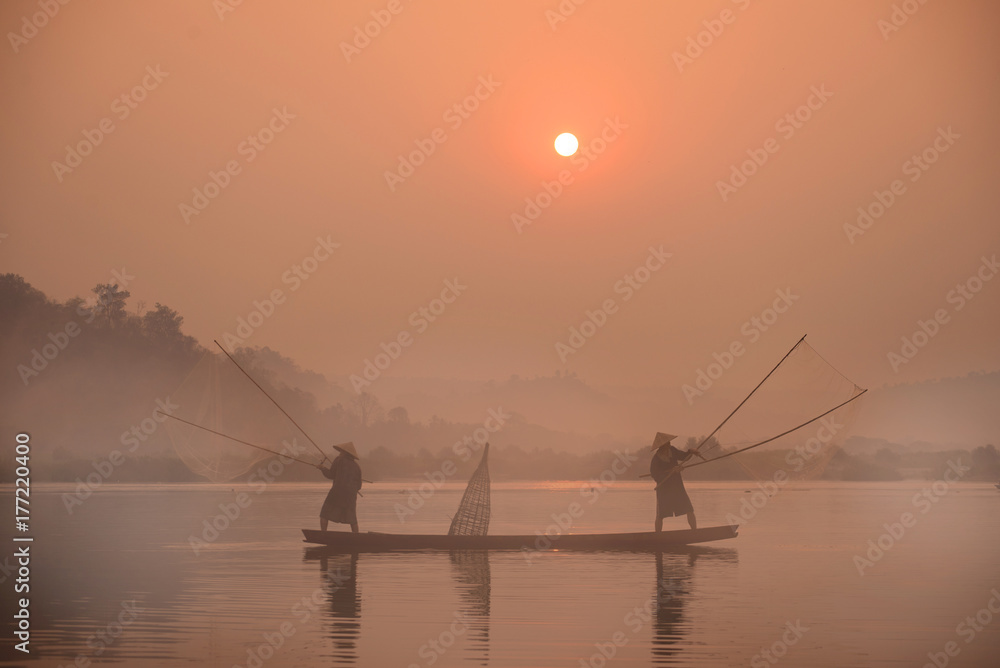 Two fishermen are fishing on the boat at Mekong river in the morning in Nong Khai, Thailand