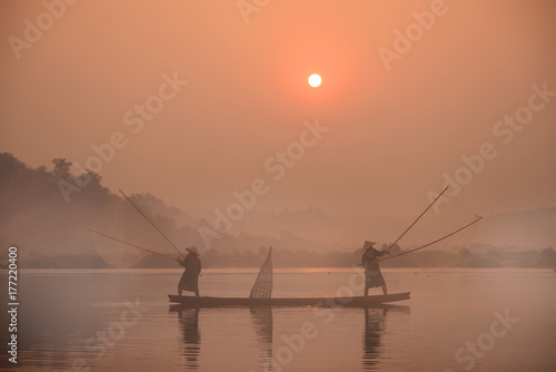 Two fishermen are fishing on the boat at Mekong river in the morning in Nong Khai, Thailand