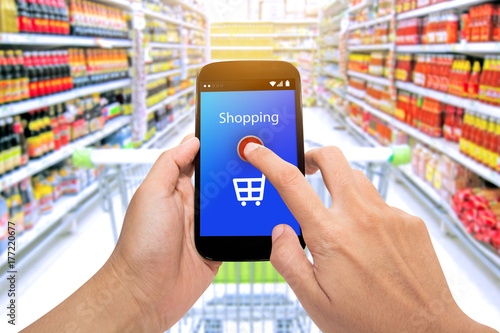 Man use mobile phone, blur image of inside supermarket background,Shopping Purchase Order Concept.