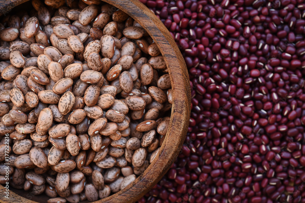 Fototapeta premium Pinto bean in wooden bowl on red bean background