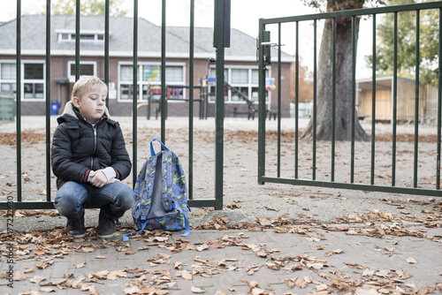 School boy forgotten by mother alone at school gate