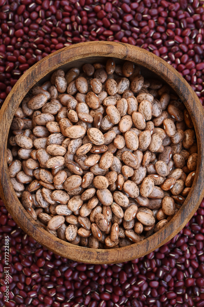 Pinto bean in wooden bowl on red bean background Pinto bean in wooden bowl on red bean background