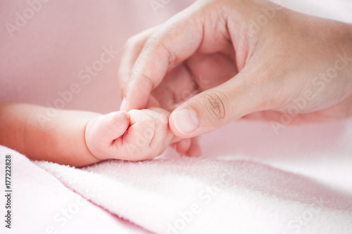 Mother hand holding asian newborn baby girl hand while she sleeping with love