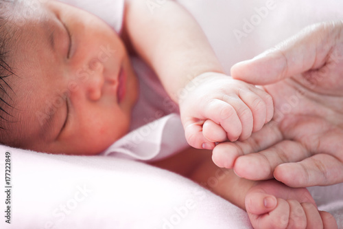 Tiny newborn baby hand holding mother finger with love in soft color tone