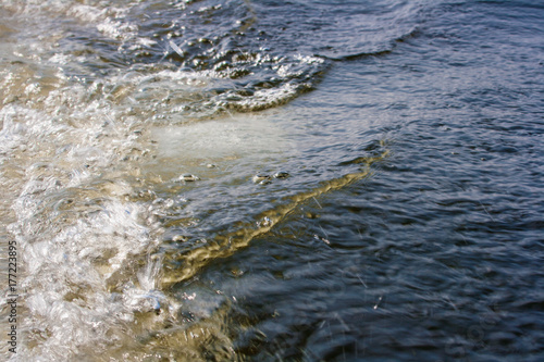 The water behind the stern of the boat. Horizontally. White water breakers from the propeller of a motor boat with sunlight reflection. 