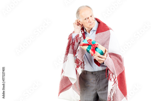 Portrait of senior man wrapped in blanket holding Christmas gift