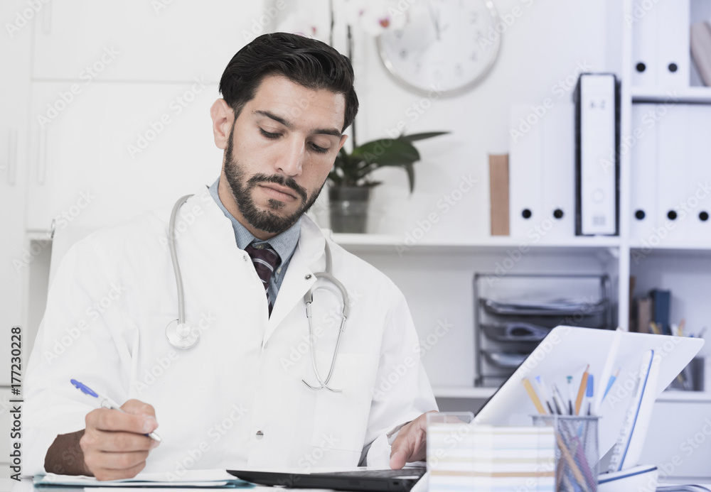 Doctor is working with documents in laptop