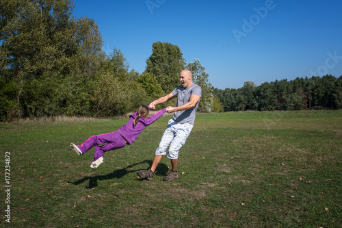 A father with daughter are playing in the park at sunny day.