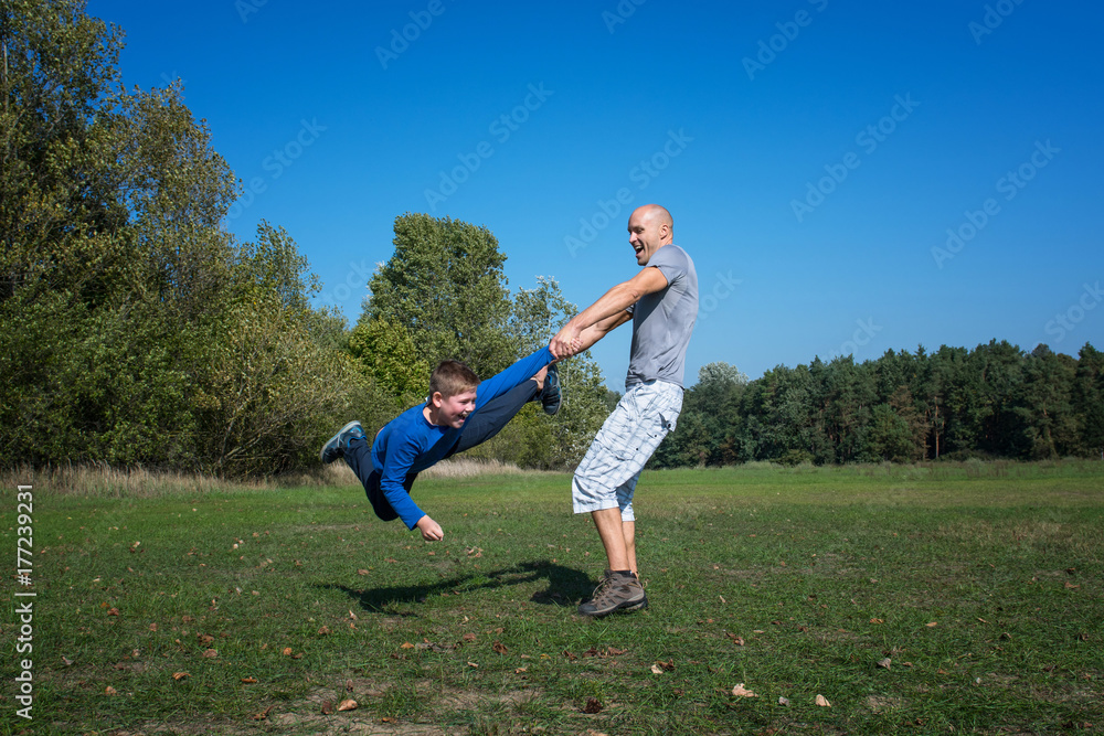 A father with son are playing in the park at sunny day.