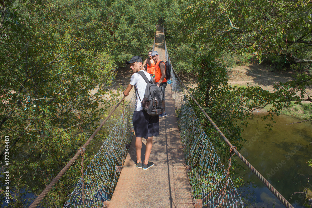 Obraz premium Trekking together. Active hikers. Travelers travel on the artificial roadway of the suspension bridge