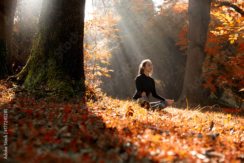 A young woman make yoga position at sunrise. in the autumn forest.