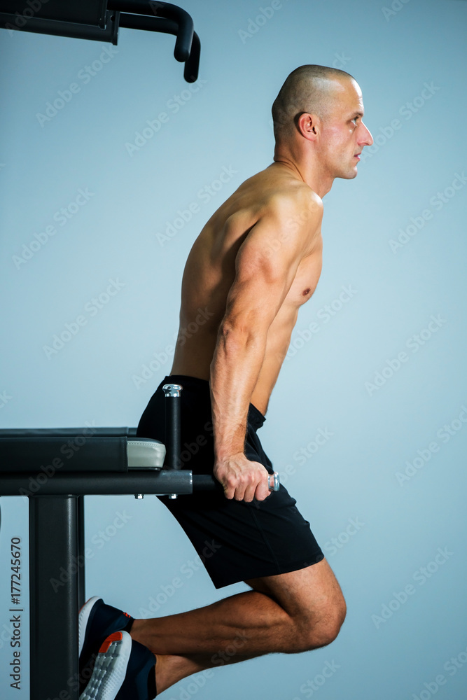 Obraz premium Adult muscle man using gym machines for working out