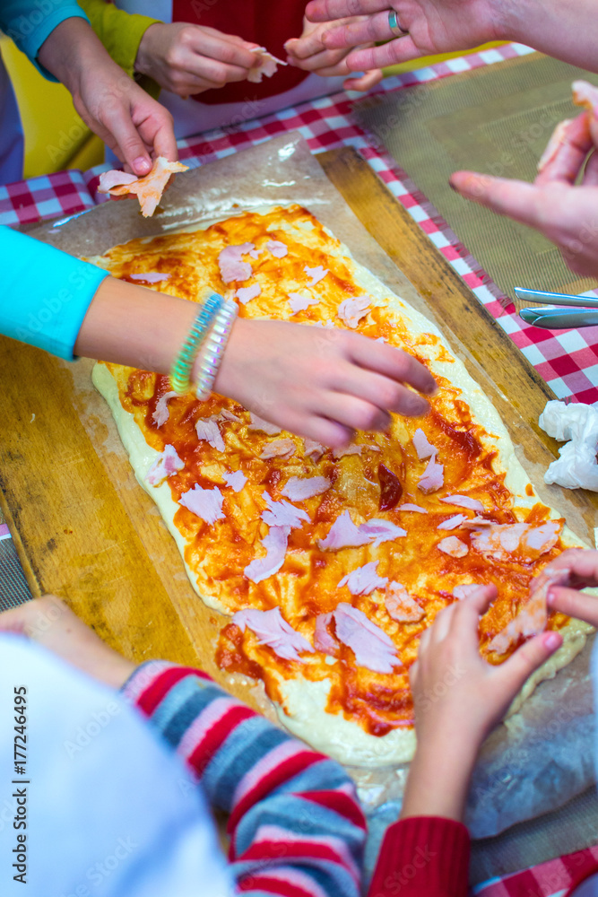 children are cooking pizza. hands in the frame