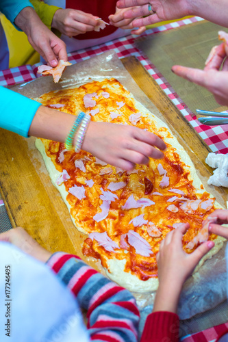 children are cooking pizza. hands in the frame