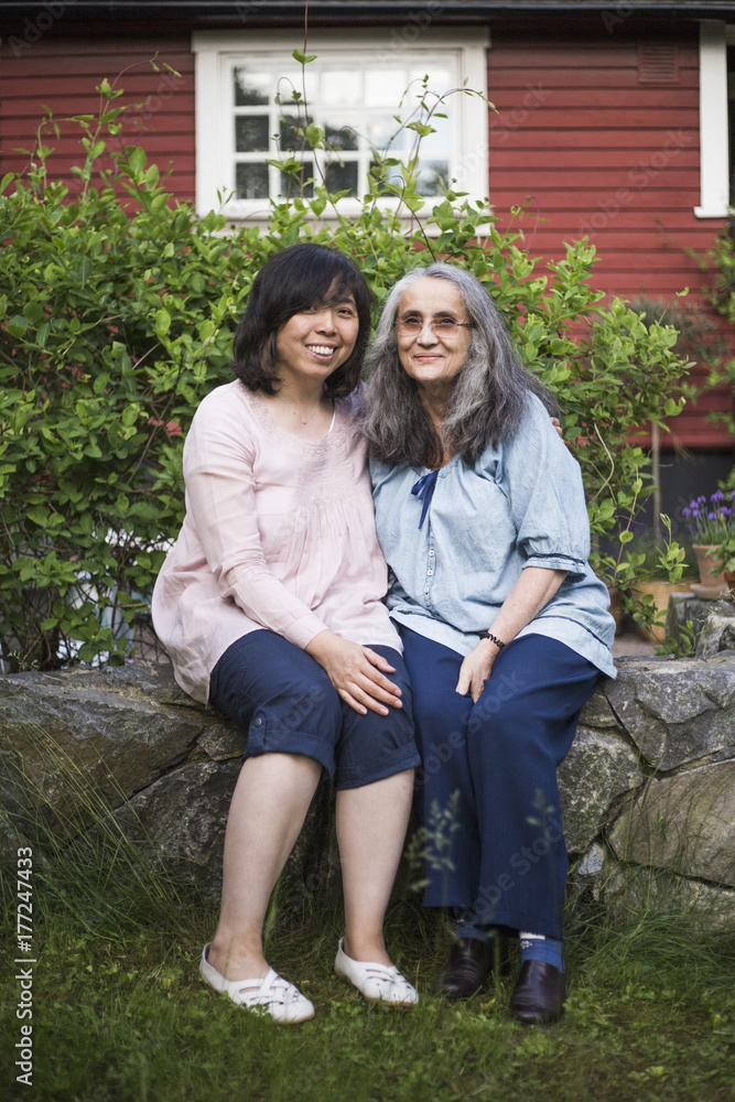 Portrait of women sitting against house Portrait of women sitting against house