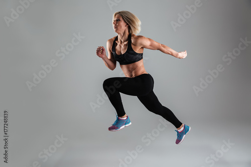 Full length portrait of a strong muscular adult woman jumping