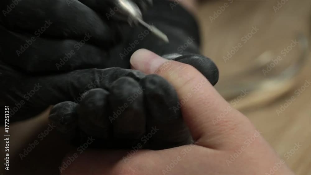 Closeup shot of hardware manicure in a beauty salon. Manicurist is applying electric nail file drill to manicure on female fingers. Closeup shot of hardware manicure in a beauty salon. Manicurist is applying electric nail file drill to manicure on female fingers.