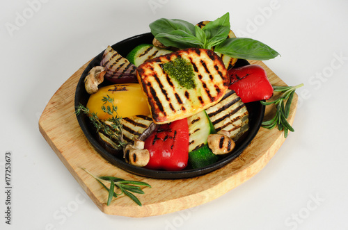 Vegetables grilled with cheese in a pan on a wooden desk