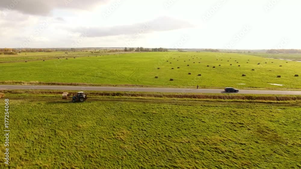 The tractor is stacking haystacks on an agricultural field in autumn, aerial view The tractor is stacking haystacks on an agricultural field in autumn, aerial view