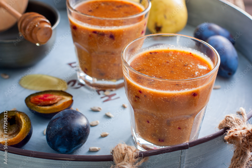 Fruity smoothies with a plum in glass glasses on a metal tray, horizontal Fruity smoothies with a plum in glass glasses on a metal tray, horizontal