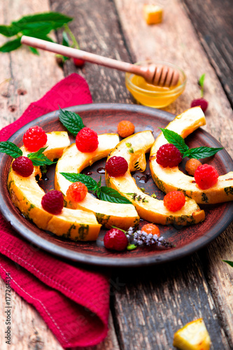 Grilled pumpkin with honey, raspberry and mint on wooden rustic background. Close up.