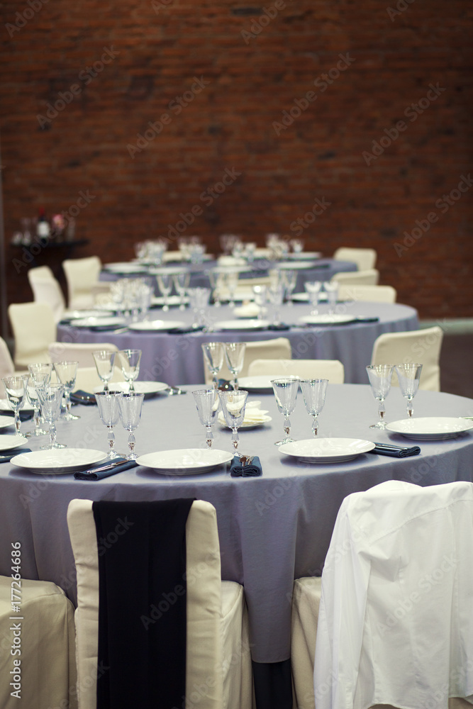 Preparation for a banquet. The tables are covered with lilac tablecloth. Wine glasses are on the tables in the restaurant. Preparation for a banquet. The tables are covered with lilac tablecloth. Wine glasses are on the tables in the restaurant.