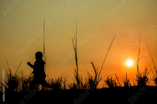Boy running on the meadow at sunset