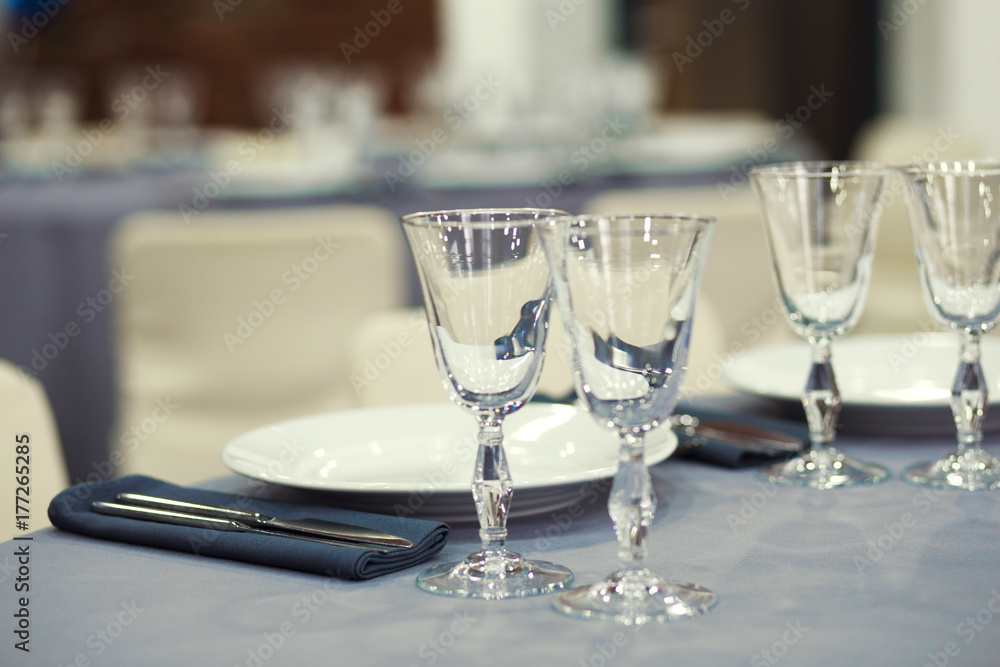 Preparation for a banquet. The tables are covered with lilac tablecloth. Wine glasses are on the tables in the restaurant.