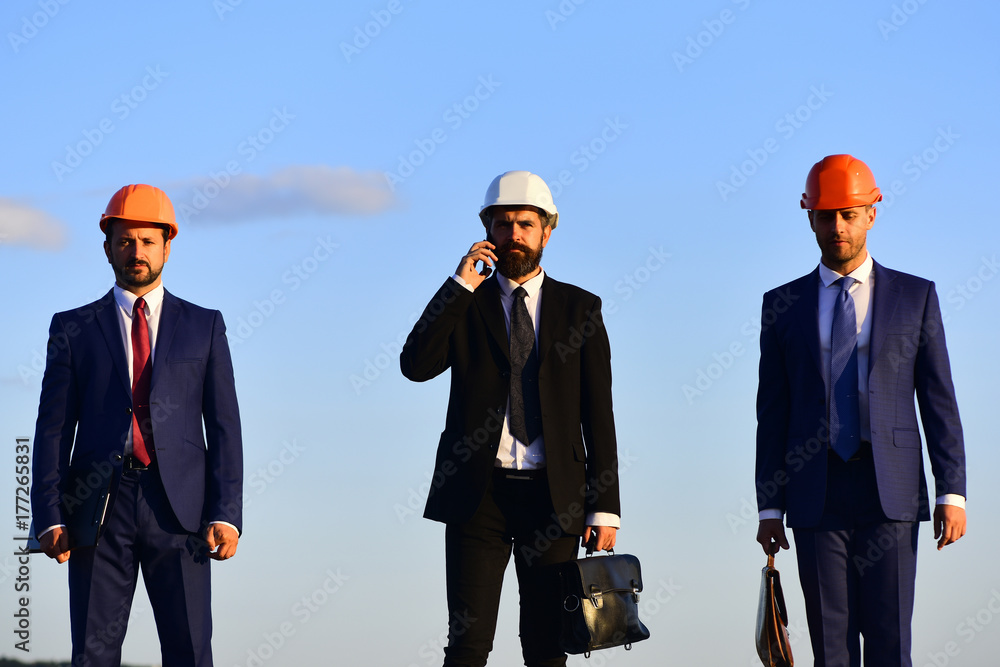 Workers and engineer hold meeting. Architects with serious faces Workers and engineer hold meeting. Architects with serious faces