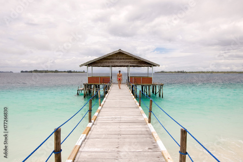 young woman walking on a pier in raja ampat archipelago